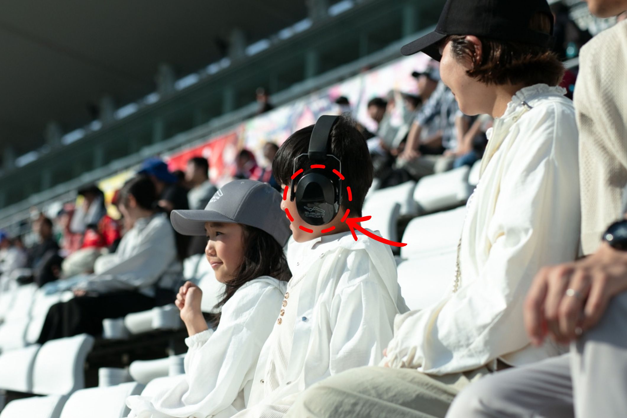 Child watching the race wearing earmuffs