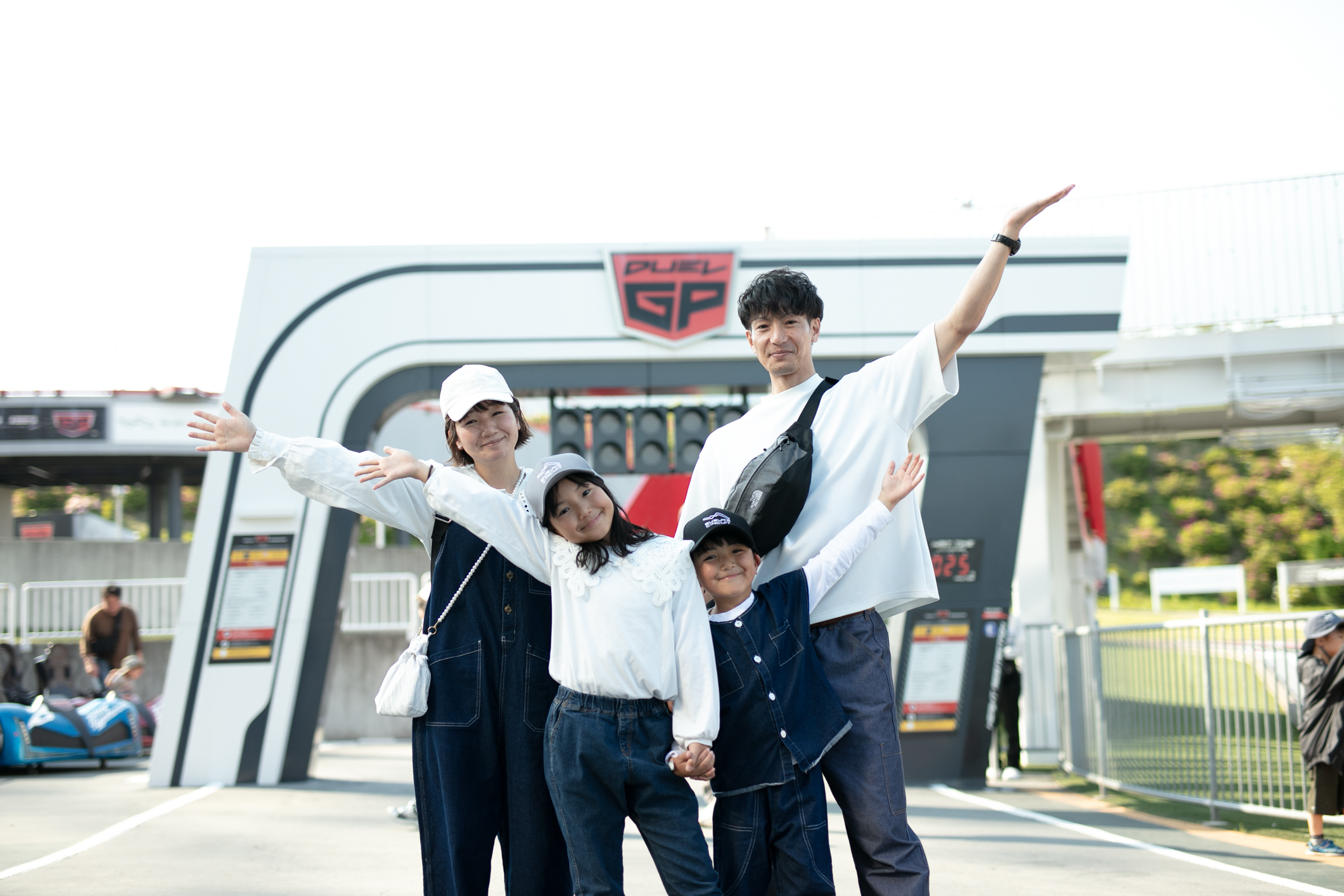 A family of four smiling with arms wide open at the entrance of Duel GP